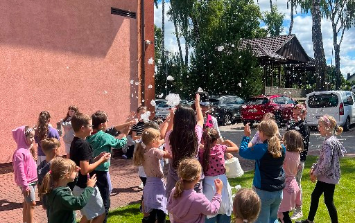 Na zdjęciu widać gromadkę dzieci, łapiące bańki mydlane